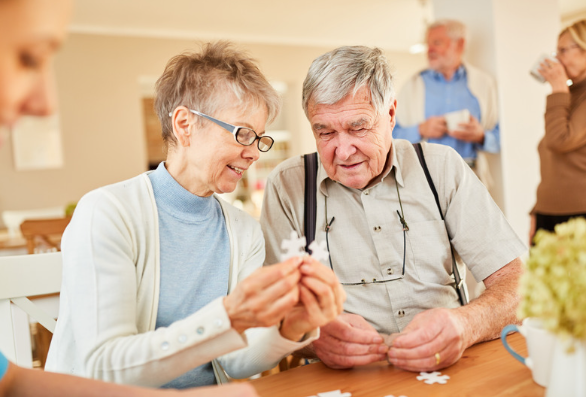 Elderly woman completing a jigsaw with an elderly man