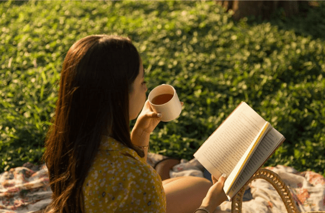 Woman reading outside with a cup of tea on a hot day