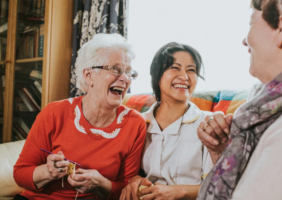 Elderly woman laughing with carer and friend