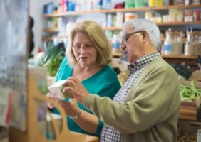 Elderly man holding a box talking to elderly woman