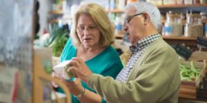 Elderly man holding a box talking to elderly woman