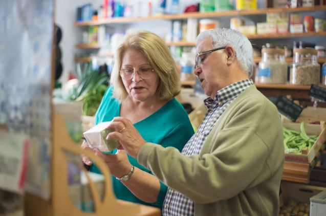 Elderly man holding a box talking to elderly woman