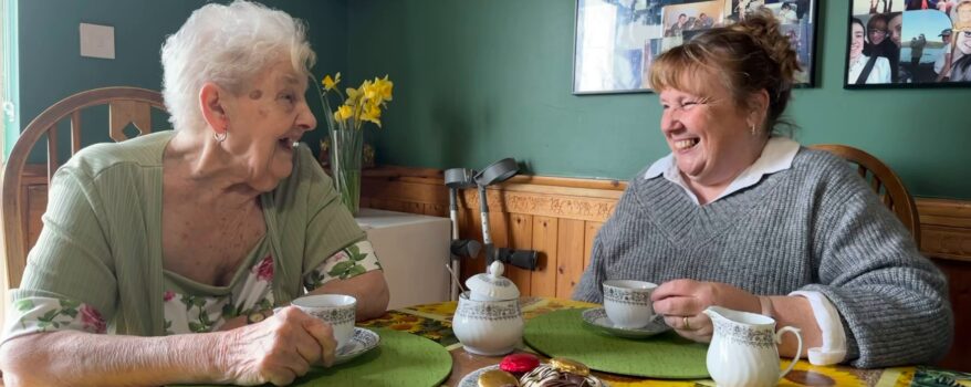 Mother and daughter in the dining room enjoying tea, biscuits and a chat