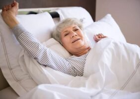 Elderly woman stretching in her bed