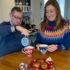 Elderly father and daughter enjoying a cup of tea together with festive Christmas jumpers on